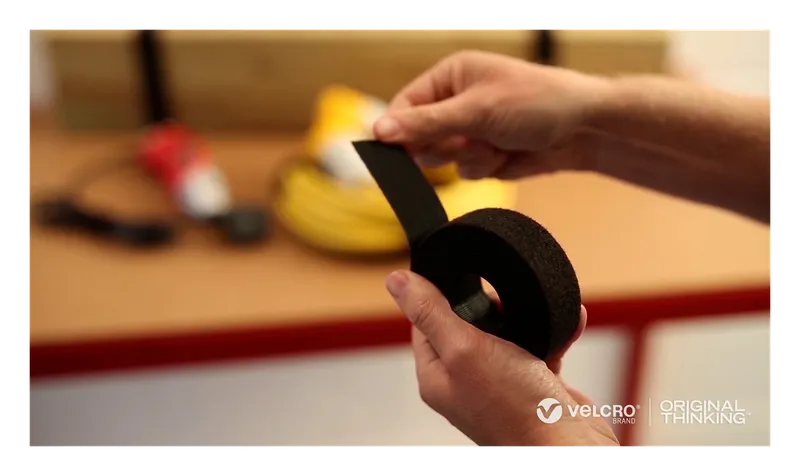 Hands cutting a length from a VELCRO Brand ONE-WRAP heavy duty roll