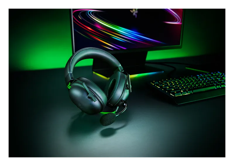 Razer BlackShark V2 X headset on a desk lit with green RGB