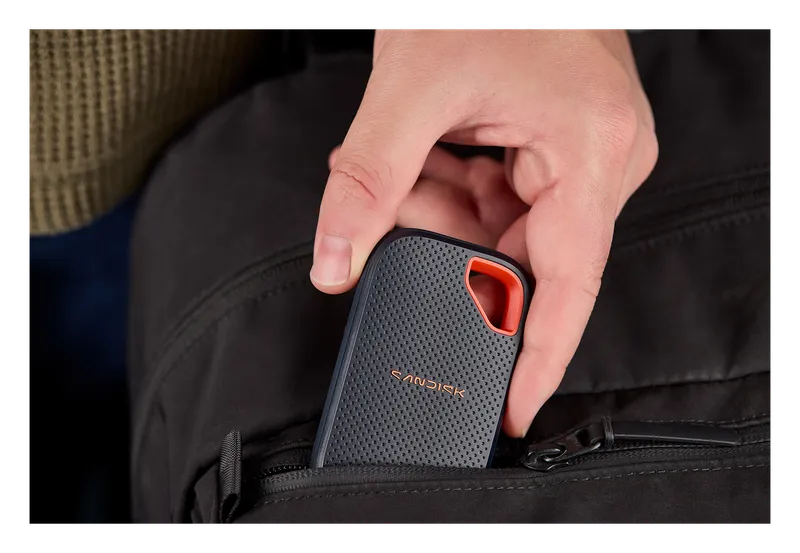 Hand sliding a SanDisk Extreme Portable SSD into a bag pocket