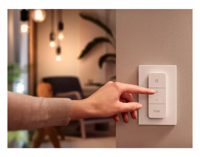 Hand pressing the Philips Hue Dimmer Switch on a wall