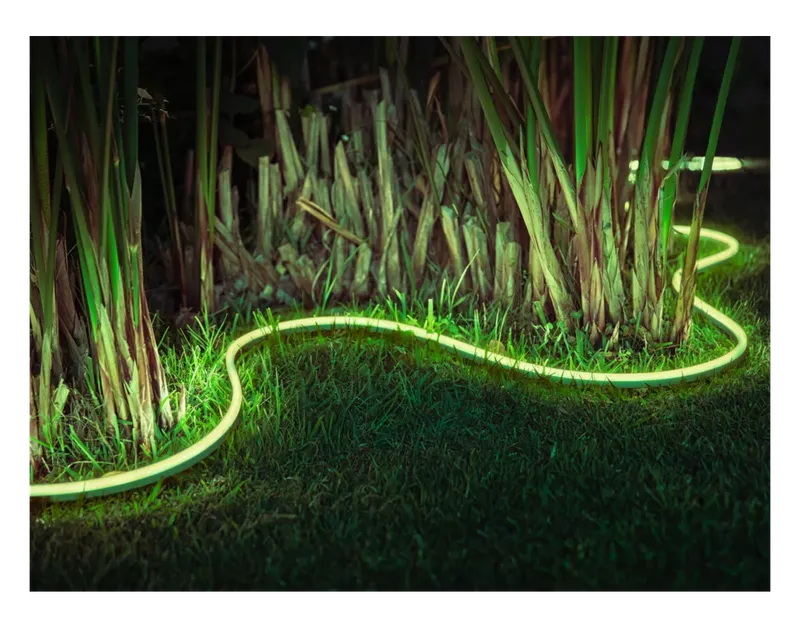 Philips Hue Outdoor Lightstrip glowing green along a garden bed